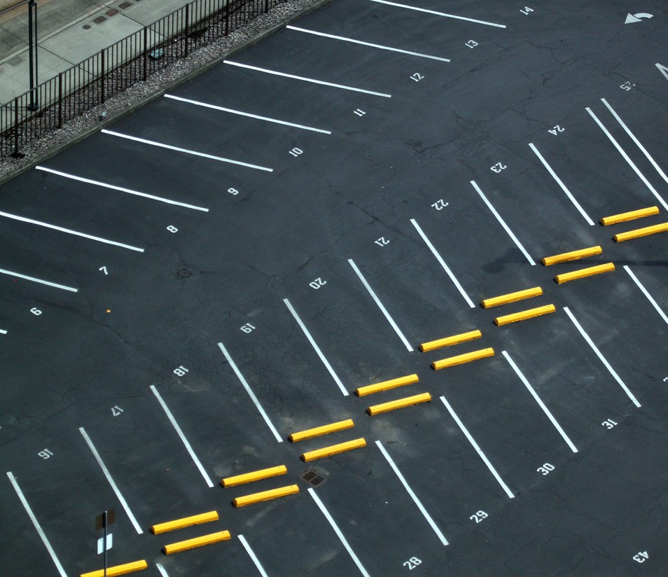 A overhead view of a parking lot with parking blocks and pavement marking lines.