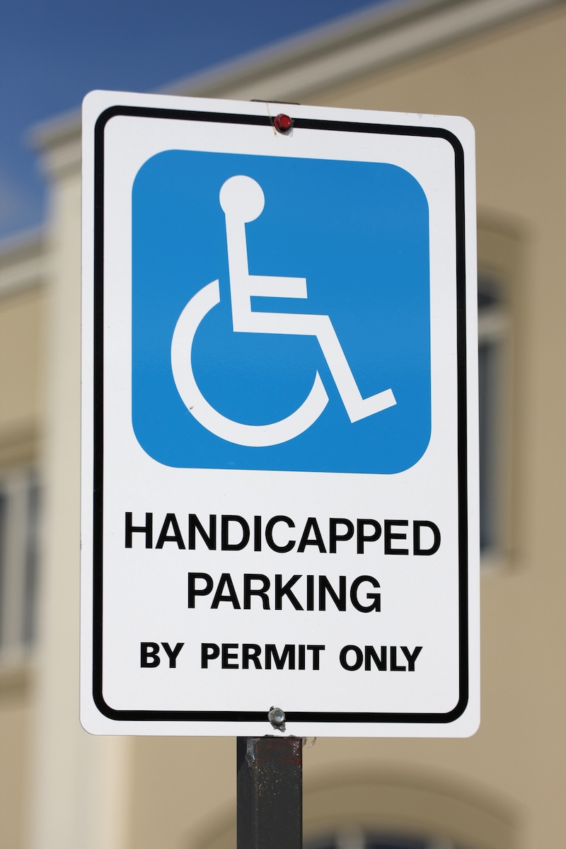 Handicapped parking sign in front of an office building, shot with shallow dof.alt