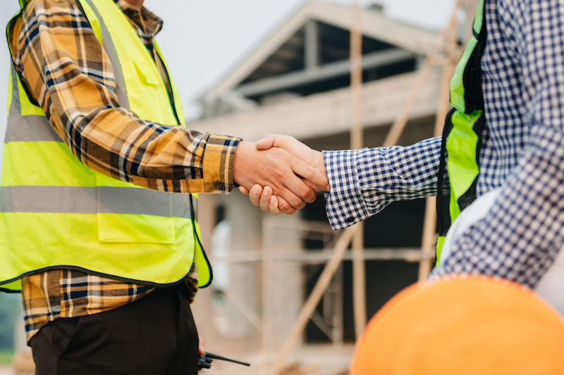 Engineer and contractor join hands after signing contract,They are having a modern building project together. successful cooperation concept in sun light