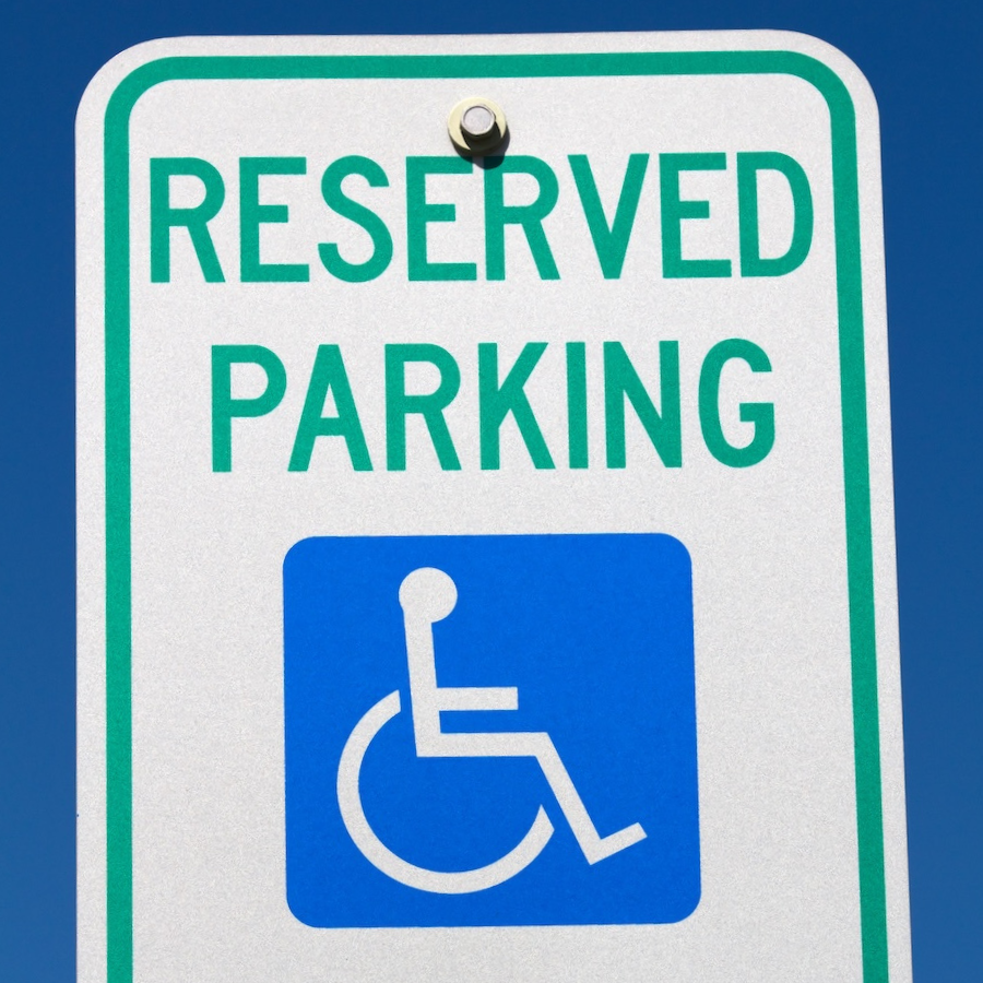 Disabled and handicapped reserved parking sign against a blue sky.